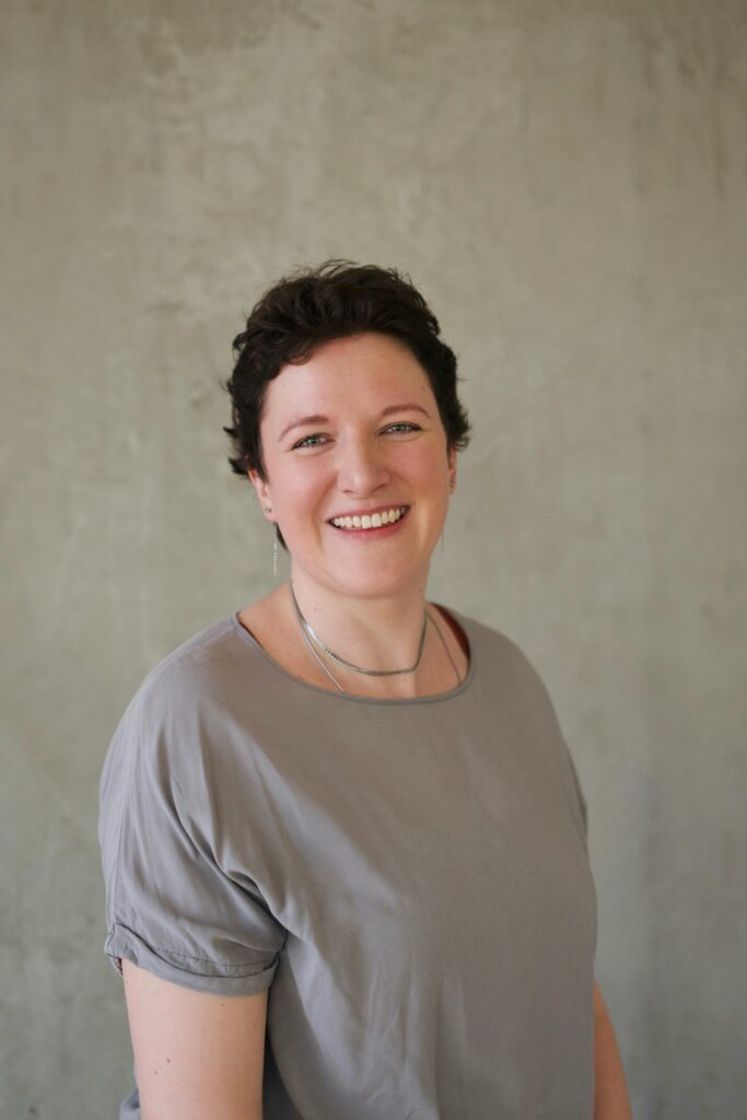 Svenja mit graum T-Shirt vor einer Betonwand.